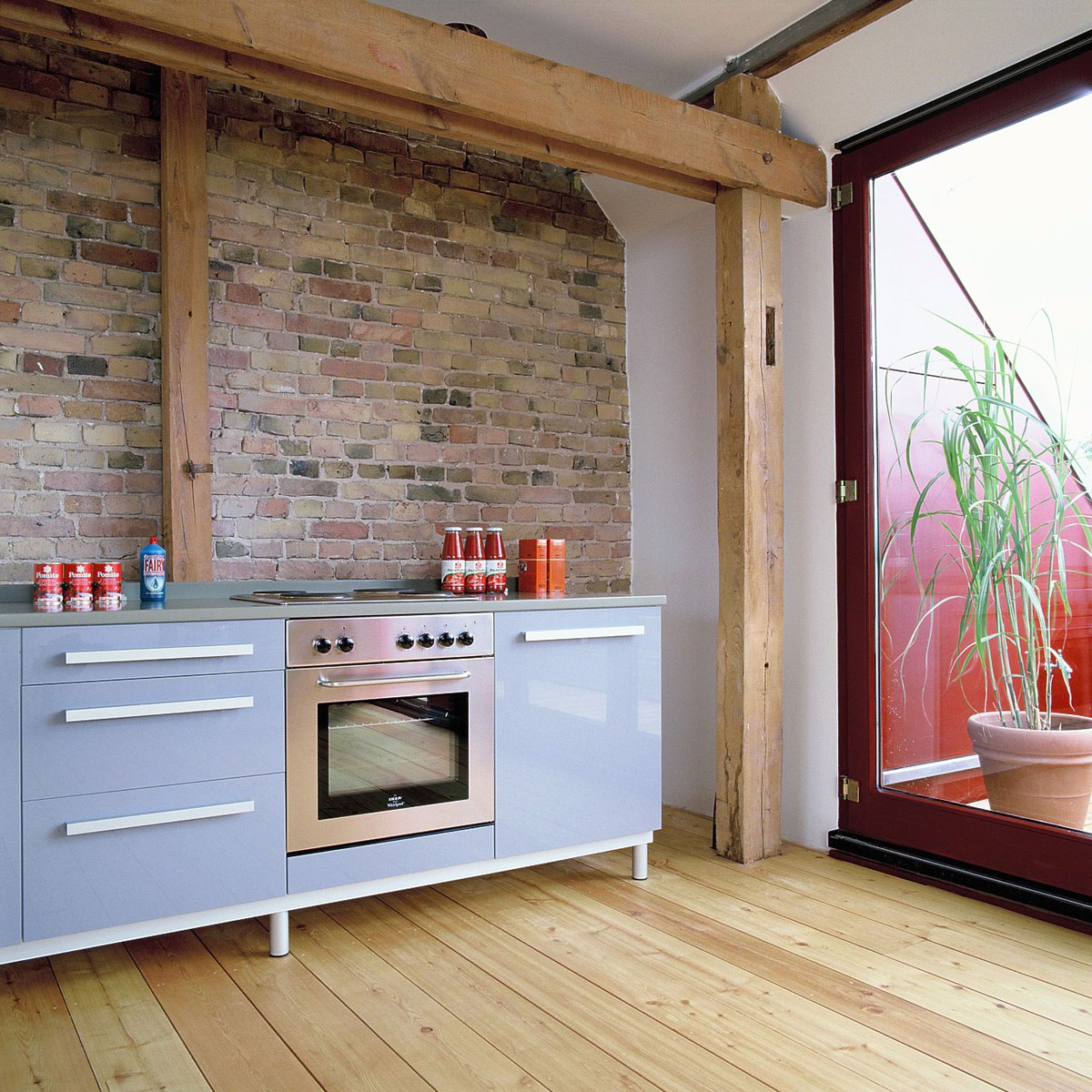 Ausbau eines Dachgeschossrohlings in Berlin für eine Baugruppe, Wohnbereich, Dachterrasse, gesandstrahlte Giebelwand und Küchenzeile