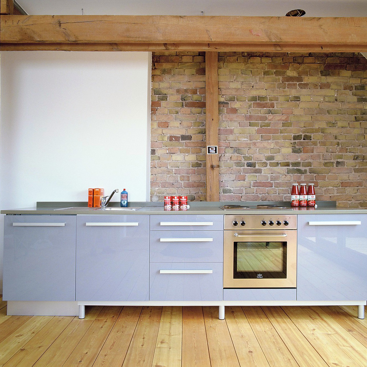 Ausbau eines Dachgeschossrohlings in Berlin für eine Baugruppe, Wohnbereich, Dachterrasse, gesandstrahlte Giebelwand und Küchenzeile