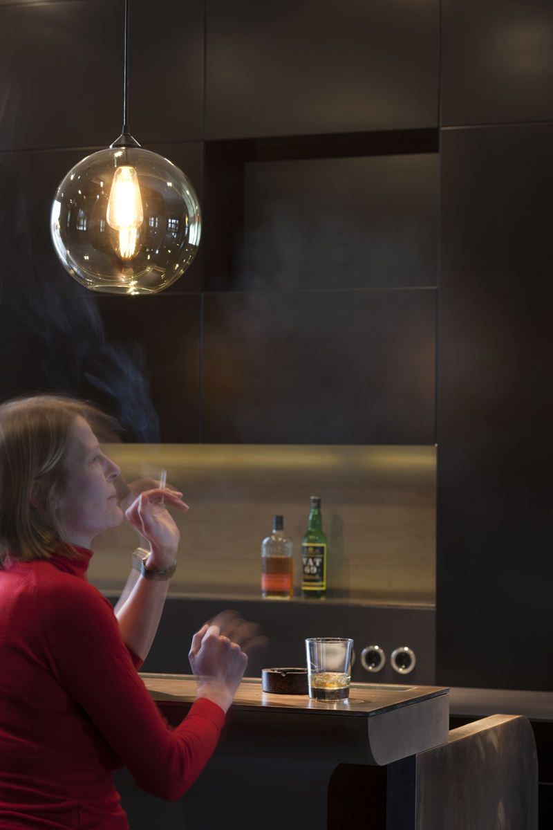 Ausbau einer Gründerzeitwohnung in Berlin, Detail Bar aus Bronze mit Gast, Anja Herold Architektin, mit Zigarette und Drink