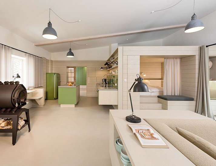 Ferienappartement Alte- Schreinerei, Werkstatt, Raumüberblick mit Alkovenbett und Bullerjan, Wandbekleidung aus 3- Schichtplatte Fichte