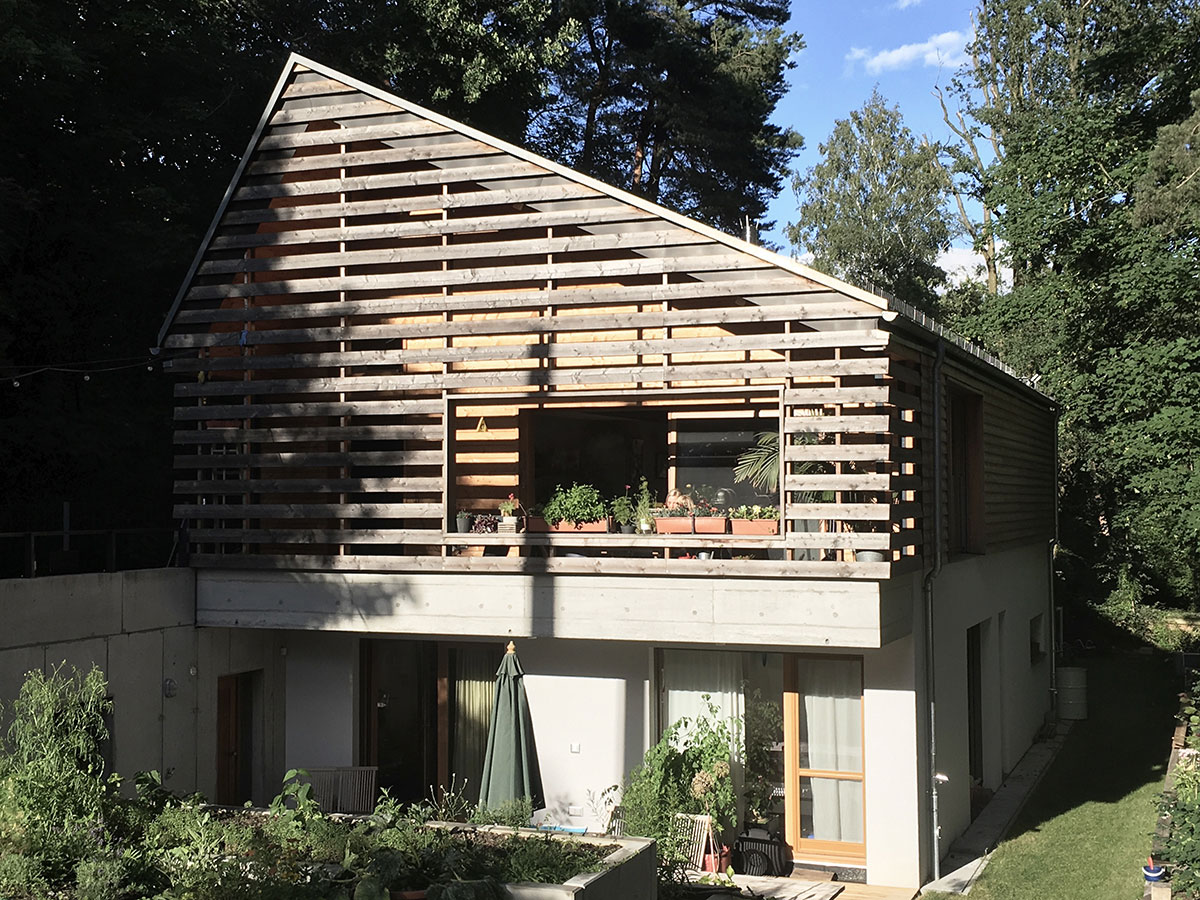 Ökologisches Einfamilienhaus in Brandenburg, Eingangsseite mit Giebelverkleidung aus Lärchenholzlamellen, terrassierte Gartenbeete