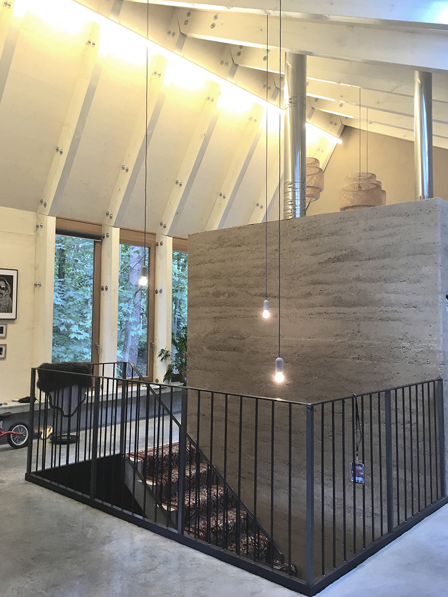 Ökologisches Einfamilienhaus in Brandenburg, Stampflehmwand mit Treppe zum Privatgeschoss, handwerkliche Detailierung Stahlgeländer